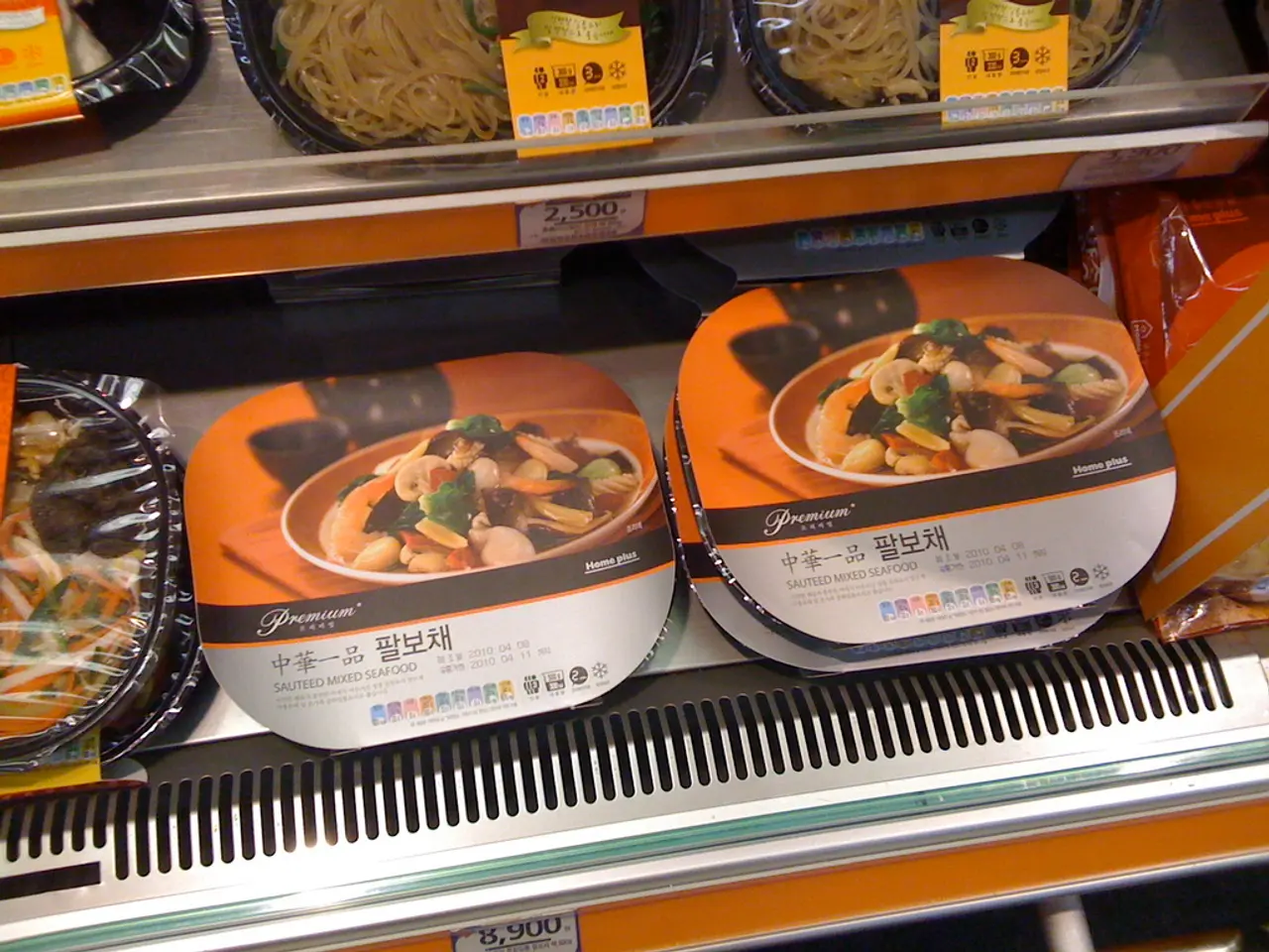 In this picture we can see food boxes in the racks. We can see price notes.