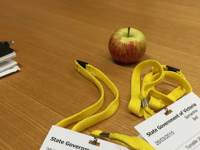 In this image I see the table on which there are 2 Id cards over here and I see an apple over here...