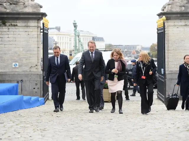 There are group of employees walking into the area,behind them there is a gate and outside the gate...